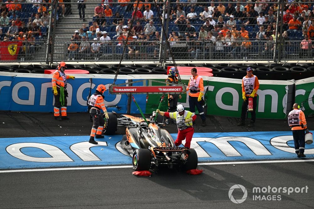 Los oficiales de pista retiran el coche dañado de Oscar Piastri, McLaren MCL60