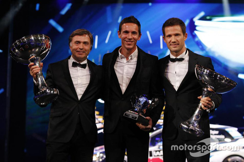 Sebastien Ogier y su copiloto Julien Ingrassia reclaman el trofeo de campeón WRC por tercer año co el jefe de VW Jost Capito.