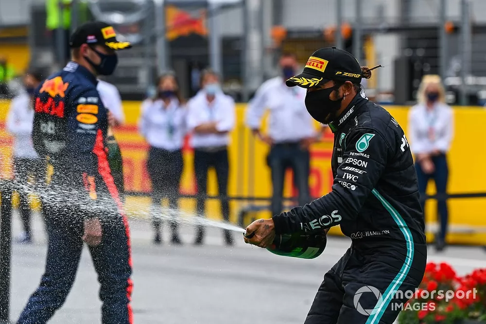 Lewis Hamilton, Mercedes-AMG Petronas F1, and Max Verstappen, Red Bull Racing spray champagne on the podium