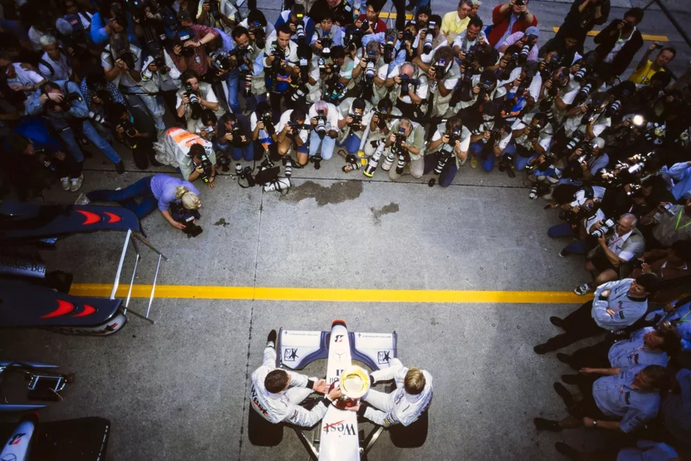 Mika H&auml;kkinen, McLaren MP4-13 Mercedes, y David Coulthard, McLaren MP4-13 Mercedes, celebran la victoria en la carrera y el campeonato del mundo frente a un a los fot&oacute;grafos.