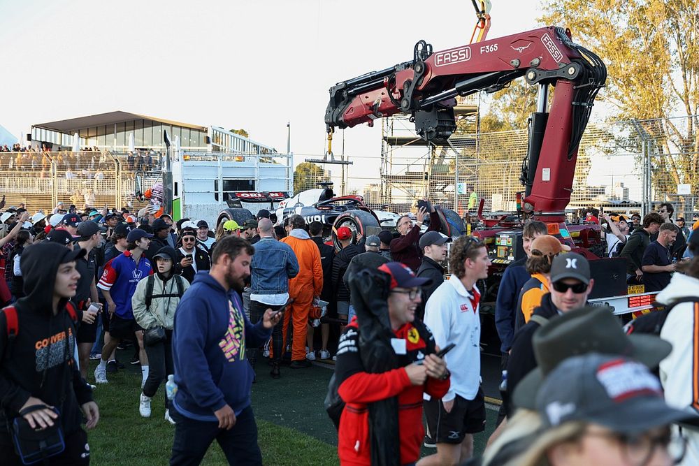 Fans invade the circuit as marshals load the car of Nyck de Vries, AlphaTauri AT04, onto a truck