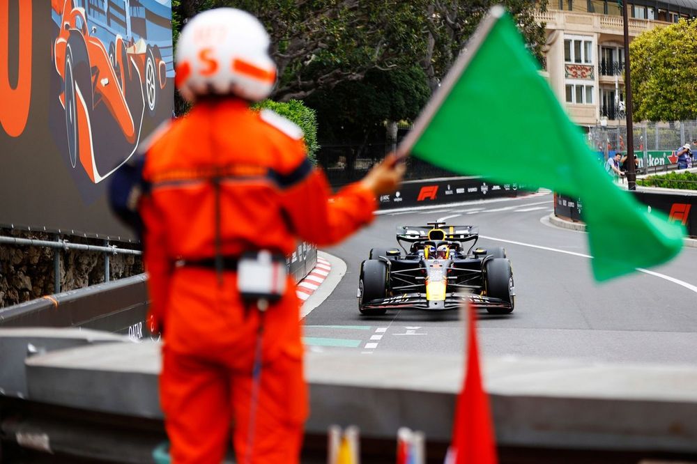 Un comisario agita una bandera verde mientras Max Verstappen, Red Bull Racing RB20, se acerca.