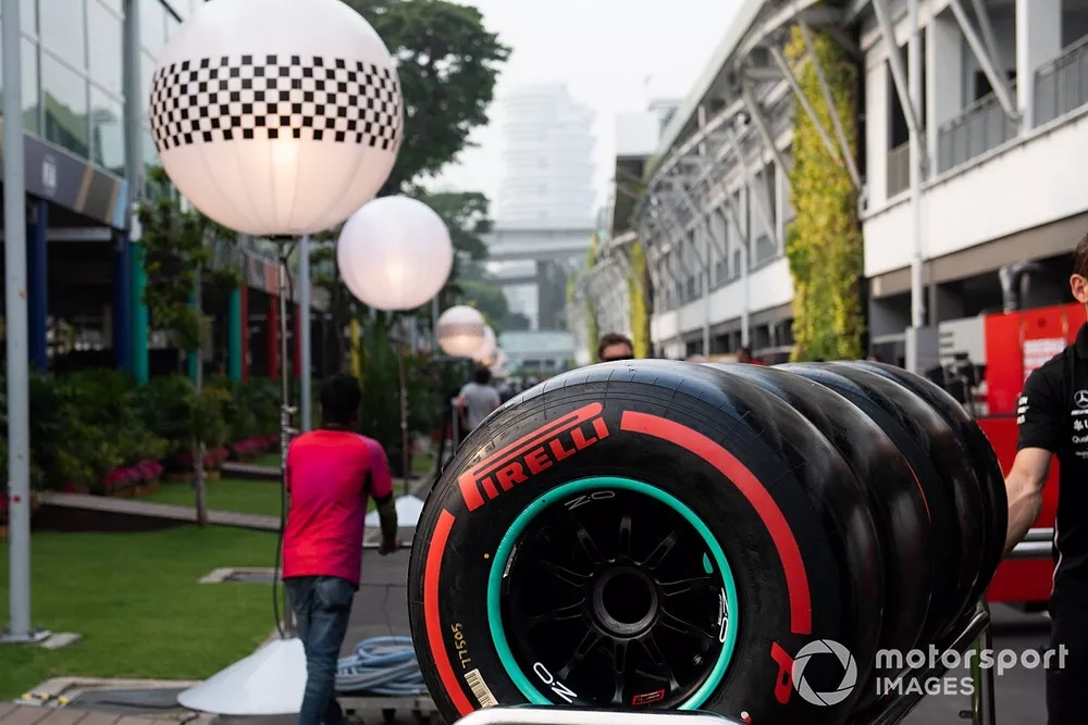Pirelli tyres are wheeled through the paddock by a Mercedes team member