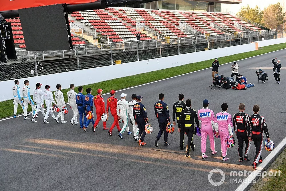The drivers walk along the track toward a group of photographers
