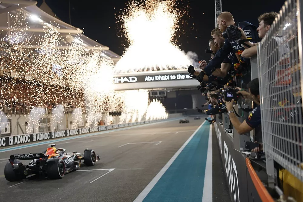 Fireworks light the sky as the Red Bull Racing team cheer Max Verstappen, Red Bull Racing RB19, 1st position, over the line from the pit wall