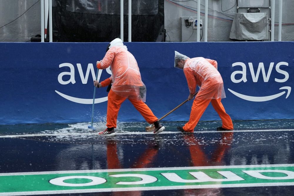 Os fiscais varrem a água no pit lane