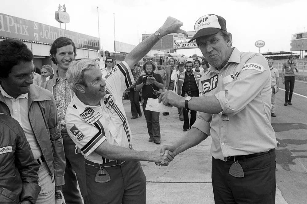 Teddy Mayer, McLaren Team Owner hands over a cheque to Ken Tyrrell, Tyrrell Team Owner after losing a pit stop tyre change competition