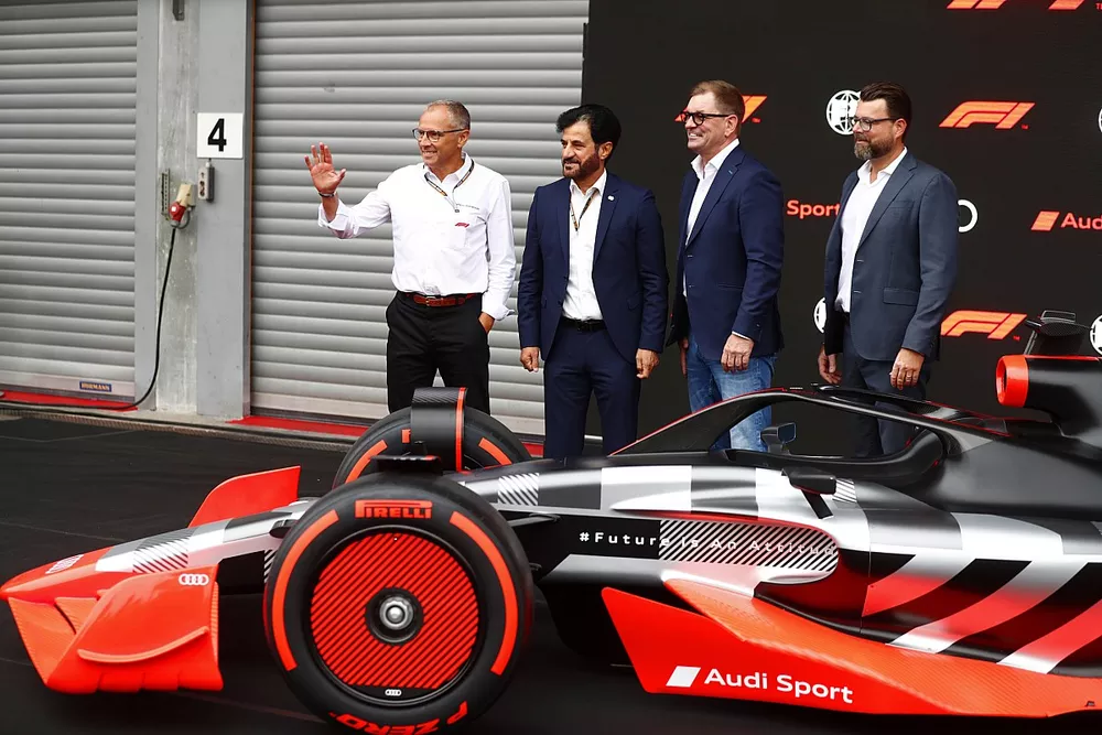 Stefano Domenicali, PDG de la Formule 1, avec Mohammed bin Sulayem, pr&eacute;sident de la FIA, Markus Duesmann, pr&eacute;sident du conseil d'administration d'Audi AG, Oliver Hoffmann, patron du d&eacute;veloppement Audi Sport GmbH, derri&egrave;re la monoplace de pr&eacute;sentation