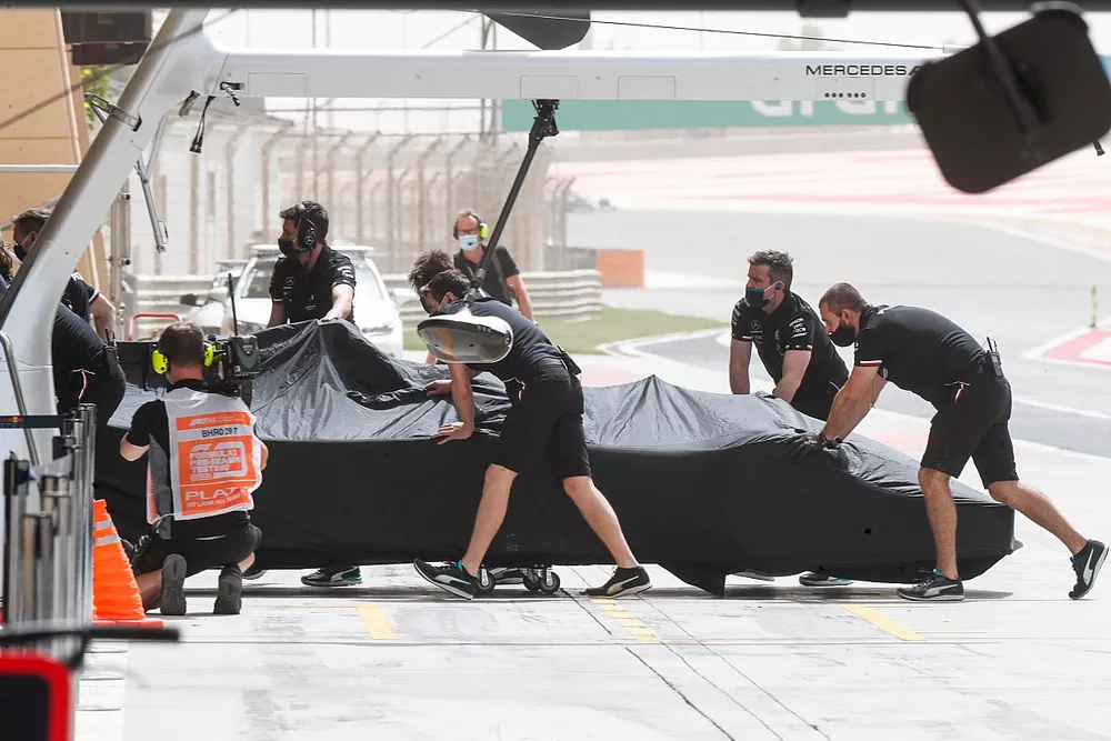 Des m&eacute;caniciens poussent la monoplace de Lewis Hamilton, Mercedes W12, dans le garage