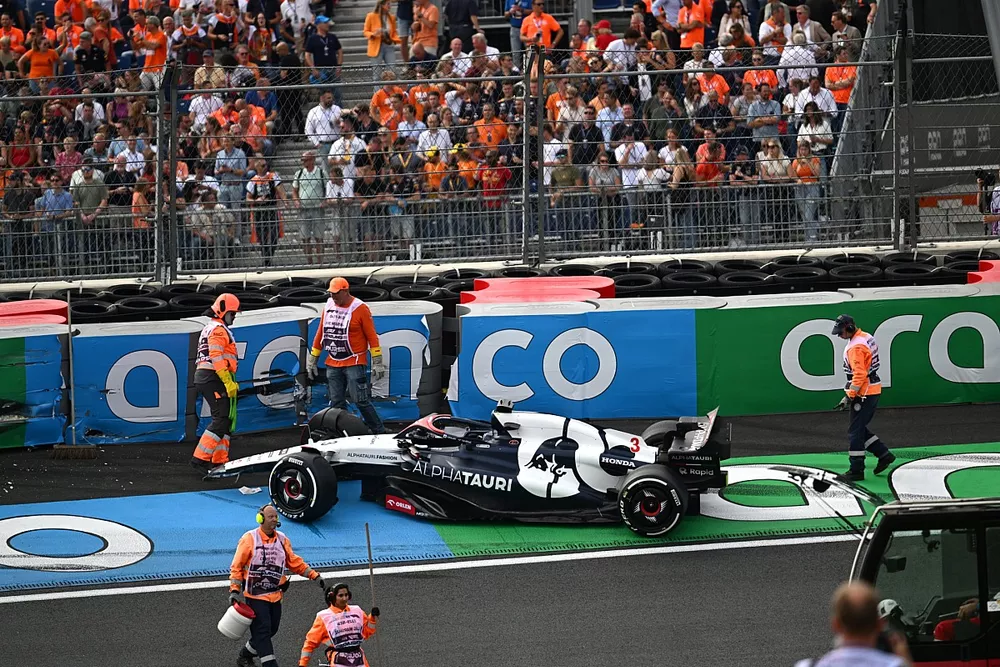 Los oficiales de pista asisten al coche da&ntilde;ado de Daniel Ricciardo, AlphaTauri AT04