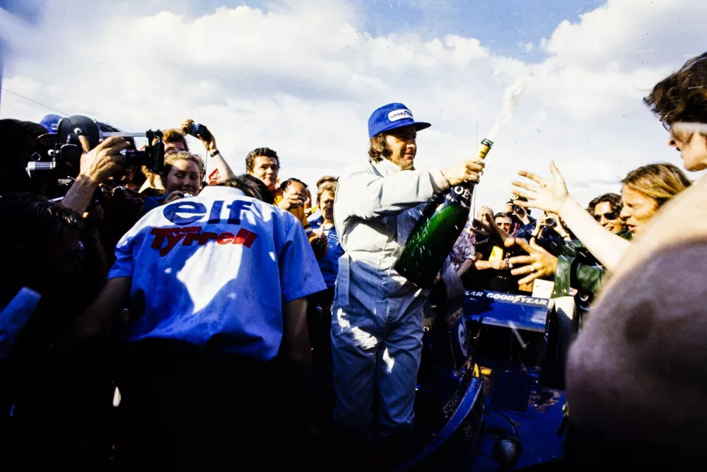 El ganador Jackie Stewart celebra con una botella de champagne