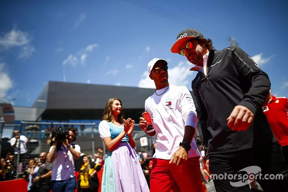 Grid Girls in national costume flank the drivers parade as Lewis Hamilton, Mercedes AMG F1, and Fernando Alonso, McLaren, pass