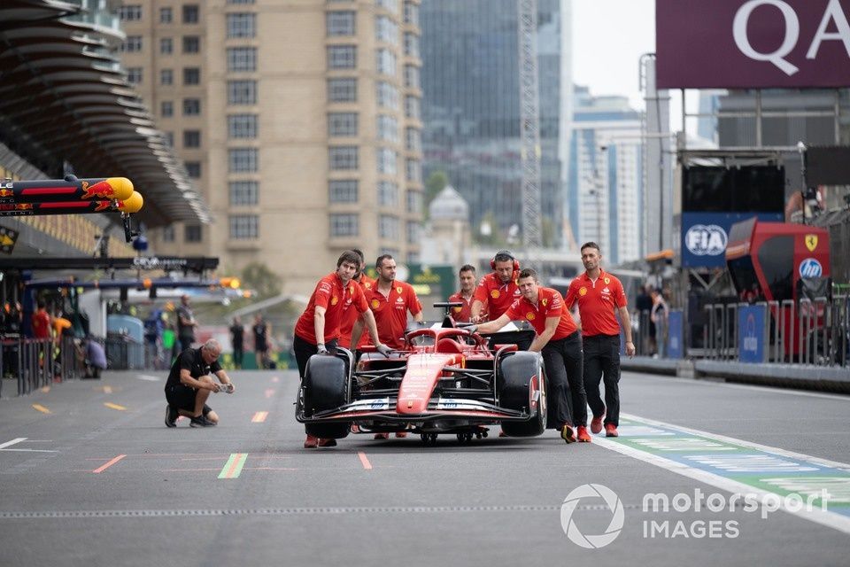 Samochód Charlesa Leclerca, Ferrari SF-24, jest zjeżdżany z pit lane przez członków zespołu.