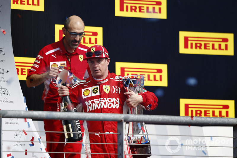 Kimi Raikkonen, Ferrari, with his champagne and trophy on the podium after winning the race
