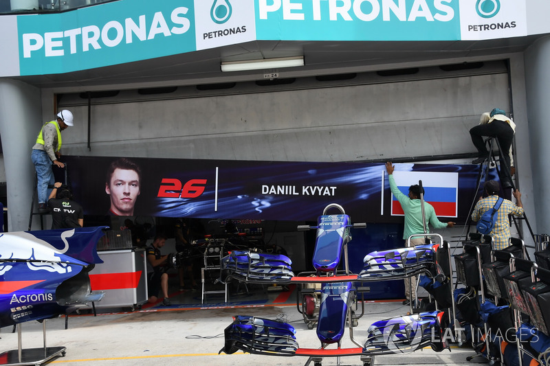 Рабочие снимают баннер с изображением Даниила Квята с гаража Toro Rosso в Малайзии