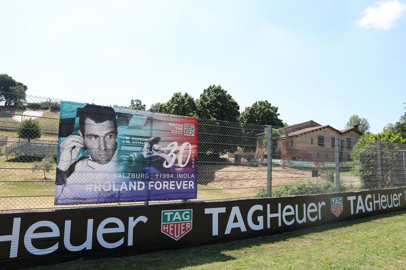 A Roland Ratzenberger flag on the fencing