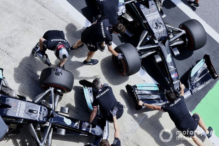 Los mecánicos mueven los coches de Valtteri Bottas, Mercedes W12, y Lewis Hamilton, Mercedes W12, en el carril de boxes