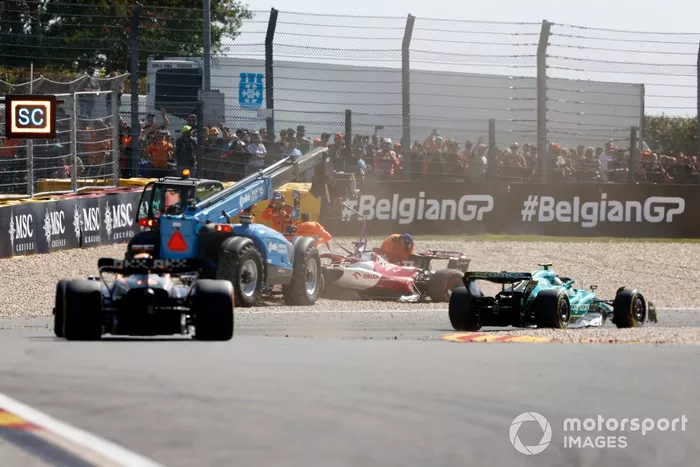 Sebastian Vettel, Aston Martin AMR22, Daniel Ricciardo, McLaren MCL36, pasa junto al coche varado de Valtteri Bottas, Alfa Romeo C42, mientras es asistido por los oficiales de pista