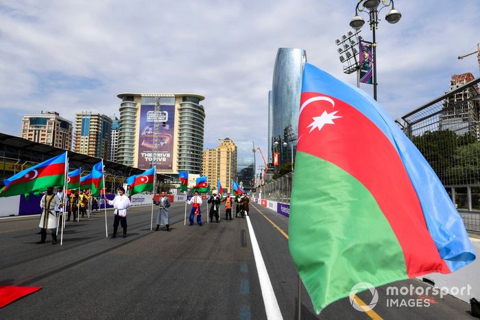 Artistas con trajes tradicionales con banderas de Azerbaiyán en la parrilla