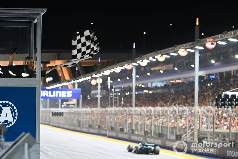 Kylie Minogue agite le drapeau à damier à la fin de la course alors que George Russell, Mercedes F1 W15, la dépasse.