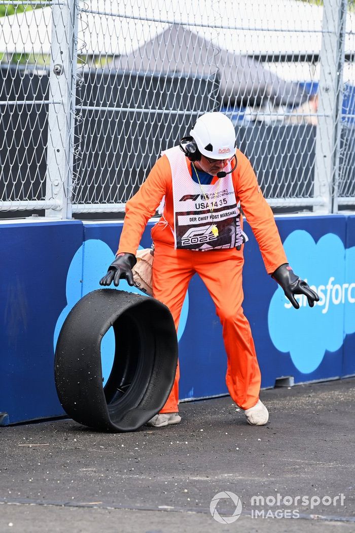 Un un oficial recupera la carcasa del neumático del coche de Lando Norris, McLaren MCL36