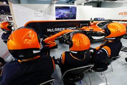 Los mecánicos de McLaren ven la carrera en el garaje con el auto de Stoffel Vandoorne, McLaren MCL32