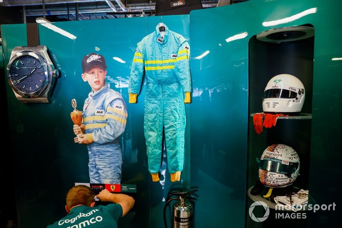 Un sticker de un joven Sebastian Vettel en el garaje de Aston Martin con su primer casco de carreras y el último.