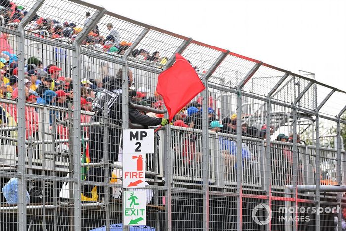 Oficiales de pista despliegan la bandera roja en la calificación