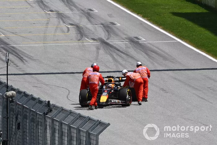 Los comisarios empujan el coche de Max Verstappen, Red Bull Racing RB20, de vuelta a su garaje.