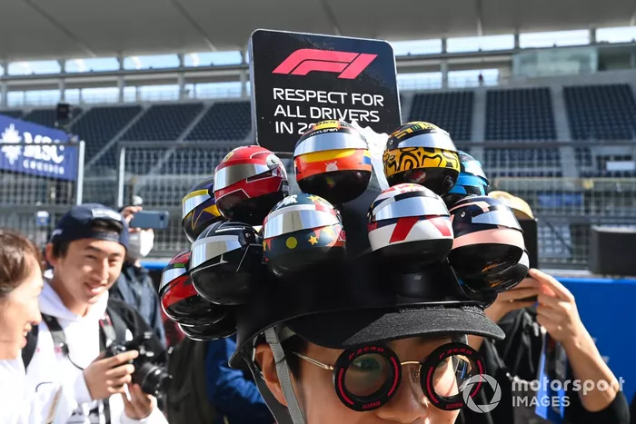 Un fan portant une casquette avec les casques des pilotes dans la voie des stands