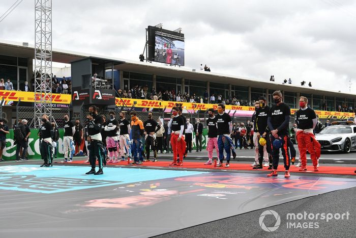 Los pilotos se ponen de pie para el himno nacional antes de la salida en sus camisetas de 