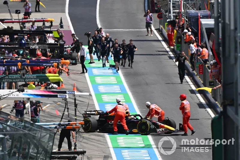 Les commissaires poussent la voiture arrêtée de Max Verstappen, Red Bull Racing RB20, dans la voie des stands.