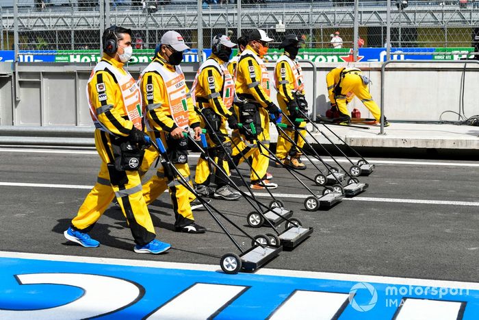 Los oficiales de pista barren el pit lane