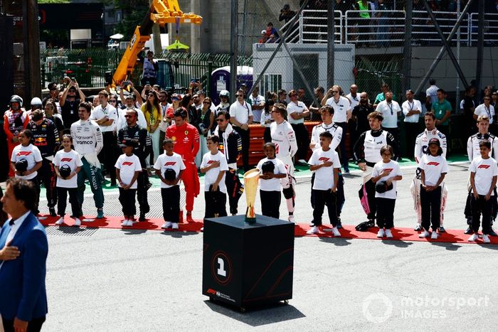 Los pilotos en la parrilla con los niños de la parrilla para el himno nacional