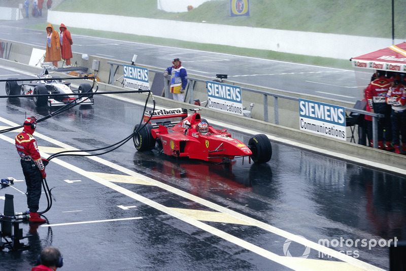 Michael Schumacher, Ferrari F300, with missing front wheel and wing, and David Coulthard, McLaren MP4-13 Mercedes, with missing rear wing, in the pitlane