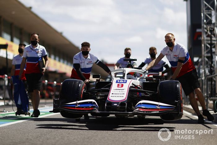 Los mecánicos empujan el coche de Nikita Mazepin, Haas VF-21, por el pitlane