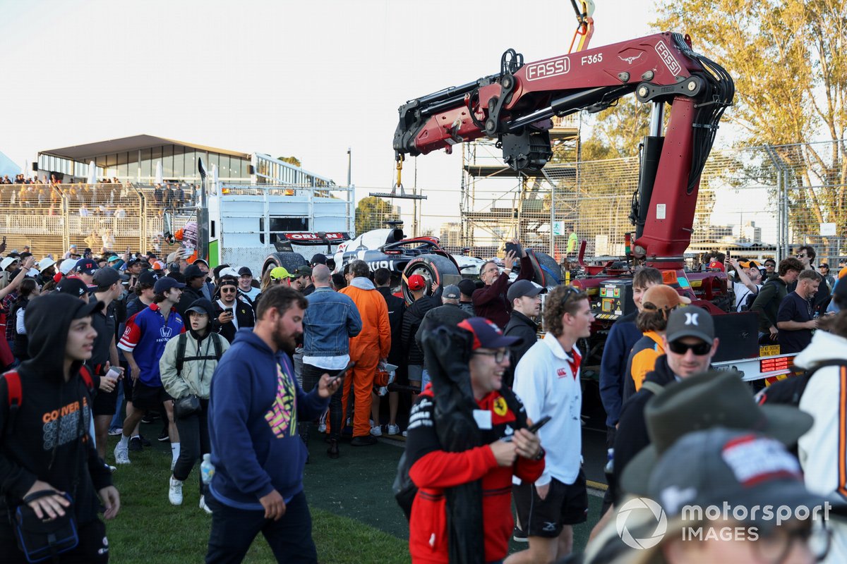 Fans invade the circuit as marshals load the car of Nyck de Vries, AlphaTauri AT04, onto a truck