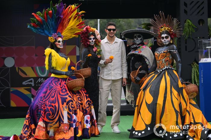 Esteban Ocon, Alpine F1 Team, con una caléndula mexicana en la mano, posa con mujeres maquilladas con Calaveras