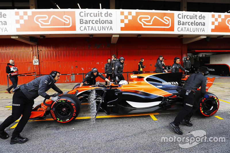 McLaren team members push the McLaren MCL32 of Fernando Alonso, McLaren, in the pit lane