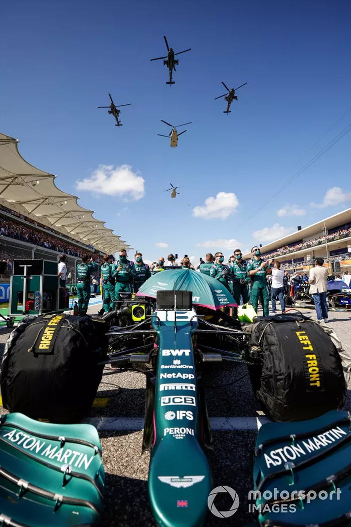Miembros del equipo Aston Martin en la parrilla de salida con el coche de Lance Stroll, Aston Martin AMR21, mientras un quinteto de helicópteros del ejército estadounidense sobrevuela la parrilla de salida