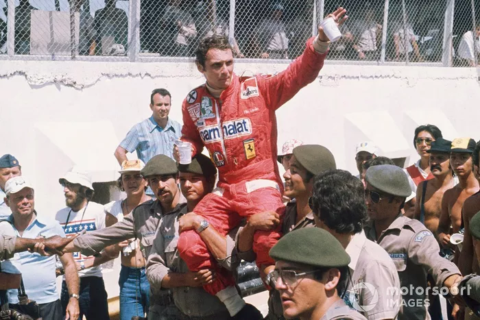 Niki Lauda, Ferrari 312T, 1ª posición es llevado a hombros de soldados entre la multitud en el paddock, retrato