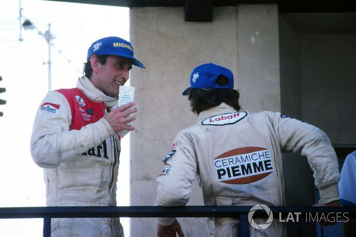 Wyczerpany zwycięzca wyścigu Gilles Villeneuve, Ferrari, i John Watson, McLaren, czekają na podium na K