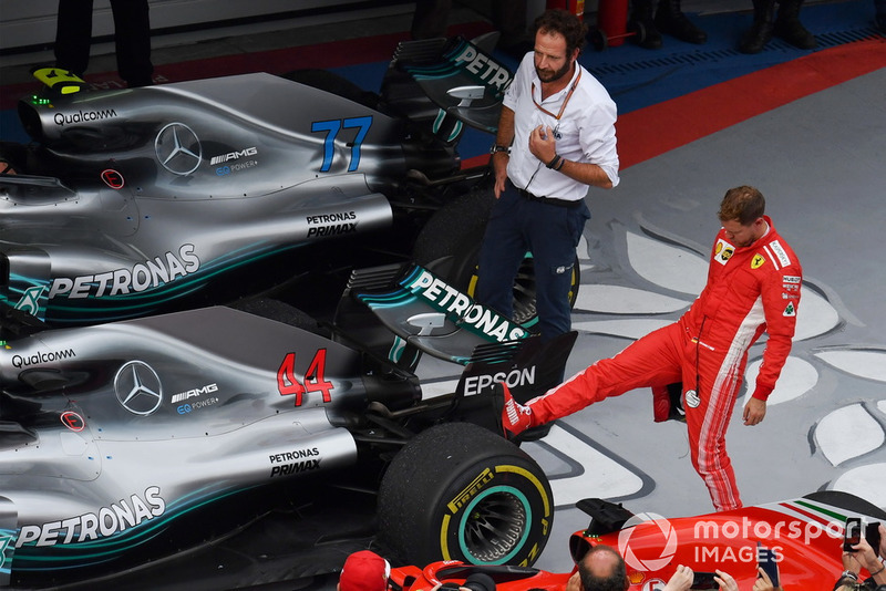 Sebastian Vettel, Ferrari regarde le pneu arrière de la voiture de Lewis Hamilton, Mercedes-AMG F1 W09 dans le Parc Fermé