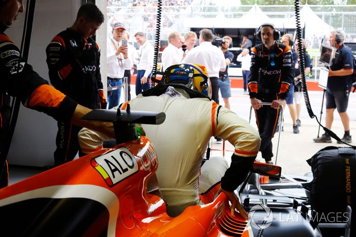 Fernando Alonso, McLaren, enters his cockpit in the garage