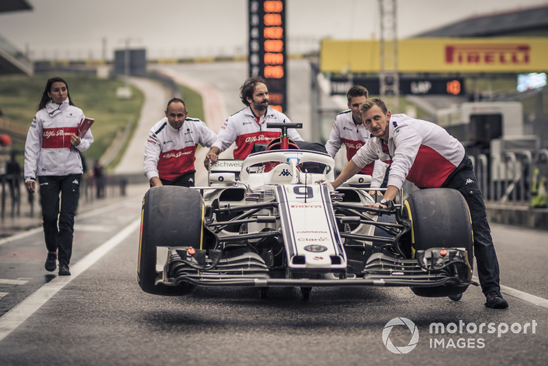 Des mécaniciens Alfa Romeo Sauber F1 Team avec une Alfa Romeo Sauber C37 dans la voie des stands