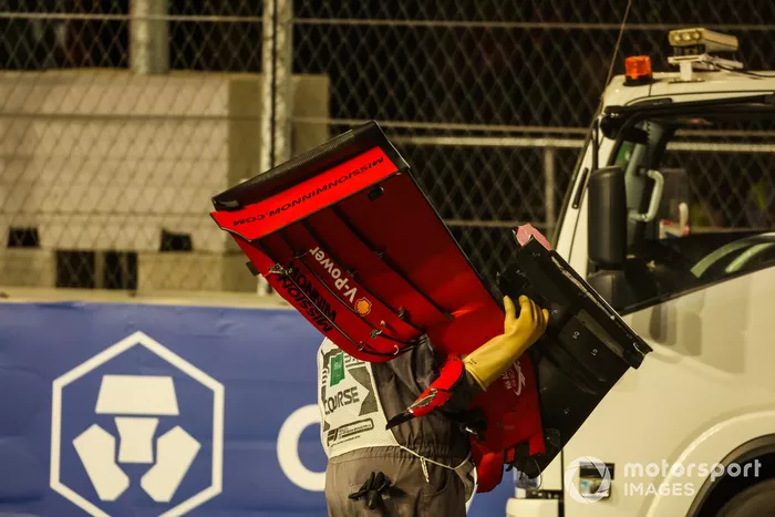 Un oficial de pista retira el alerón delantero del coche de Charles Leclerc, Ferrari SF21, del circuito