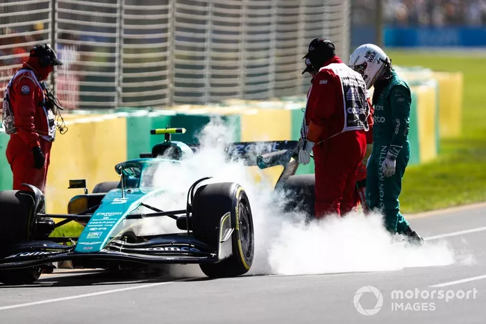 Oficiales de pista asisten a Sebastian Vettel, Aston Martin AMR22, tras abandonar en la FP1