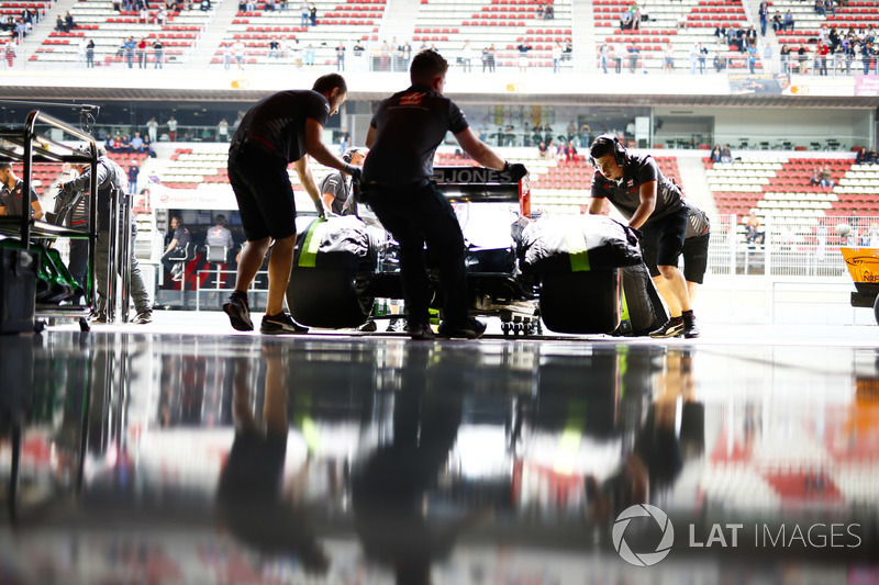 Mekanik memasukkan mobil Romain Grosjean, Haas F1 Team VF-18, ke garasi