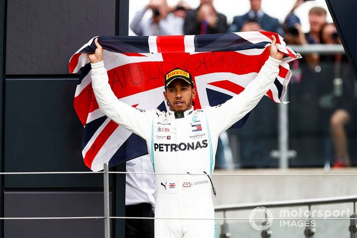 El ganador de la carrera Lewis Hamilton, Mercedes AMG F1 celebra en el podio con una bandera 