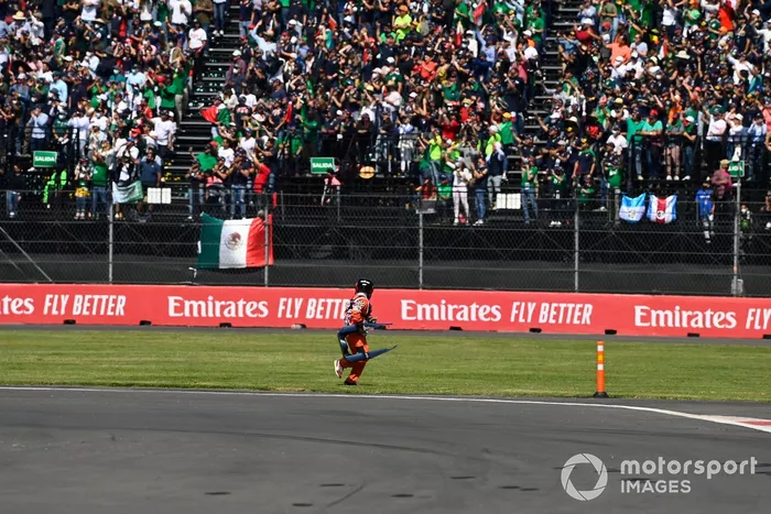 Un oficial de pista recoge las carrocerías rotas del circuito